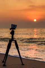 Action Camera on a tripod shooting a video of sunset over the sea.