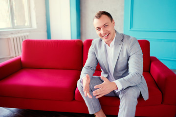 Handsome and elegant young man sitting on the red couch.