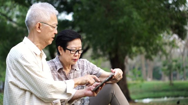 Asian senior couple using tablet together in park