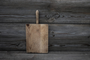Fototapeta premium Old grunge wooden cutting board on dark background. Textured kitchen desk. Food concept .