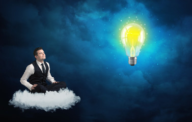 Man sitting on cloud looking at a lightbulb