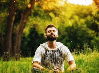 A bearded man meditating in the park