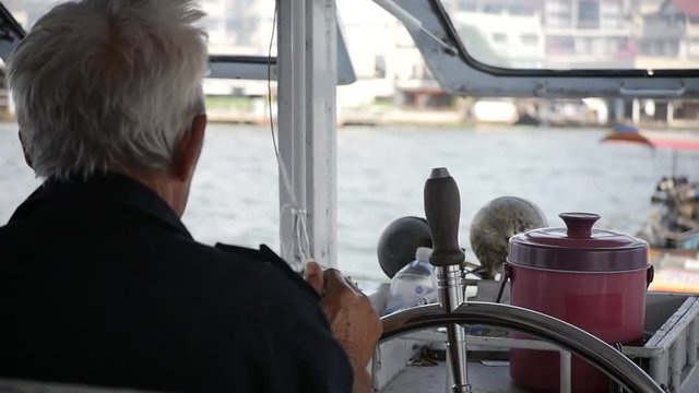 01/30/2018 Banking, Thailand, ferry across the river. An elderly man pulls up a ship, stands at the helm, turns it. HD, 1920x1080, slow motion