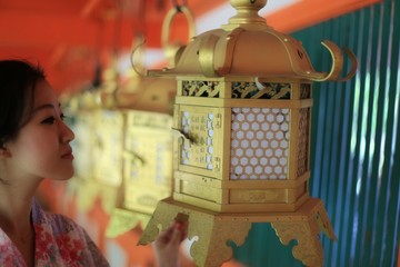 a young Japanese woman in summer kimomo (yukata) with traditional lanterns in a traditional...