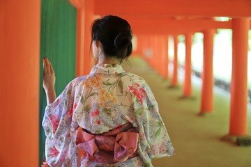A Japanese woman in summer kimono (yukata) is watching through a green window in a traditional Japanese building