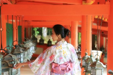 a silhouette of a young Japanese woman in summer kimono (yukata) standing at a traditional Japanese...