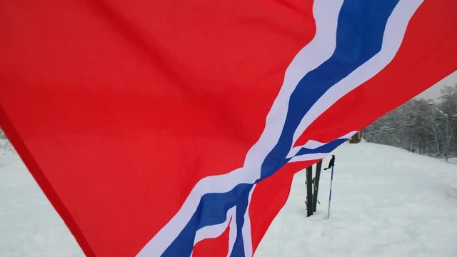 National flag of Norway waving in the wind with blurred mountains in the background