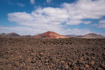 Red volcanic landscape, lava scenary with volcano crater in the background