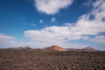 Red volcanic landscape, lava scenary with volcano crater in the background