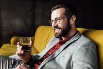 stylish cheerful man holding glass of whiskey