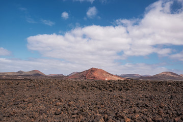 Red volcanic landscape, lava scenary with volcano crater in the background