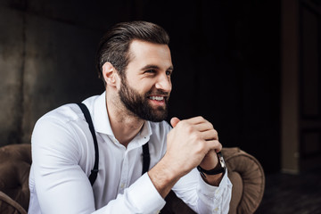 handsome stylish smiling man sitting in armchair