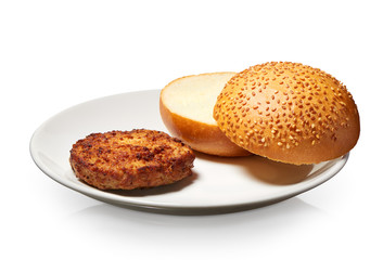 Hamburger and fresh bun with sesame seeds on white plate