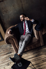 handsome stylish businessman sitting in armchair and holding cigar