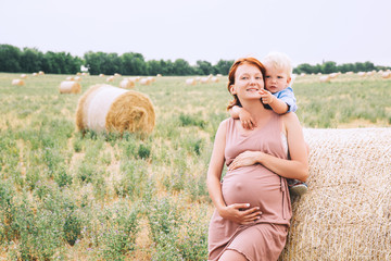 Pregnant woman and son on nature. Mother waiting of a second baby.