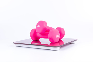 Pink dumbbells on a weighting scale