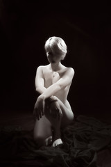 Naklejka premium Nude girl sitting on black background