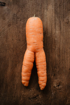 Homegrown Organic, Raw And Imperfect Carrot With A Funny, Deformed Shape On Rustic Wooden Background Ready To Be Used  As Ingredient In Healthy Root Vegetable Recipe