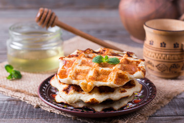 Tasty waffles with honey on plate on the table, closeup