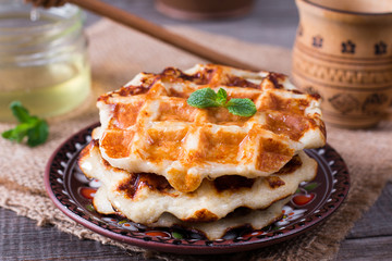 Tasty waffles with honey on plate on the table, closeup