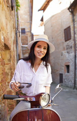 Young beautiful italian woman sitting on a italian scooter.