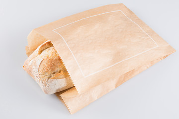 Fresh baguette in paper bag on white background