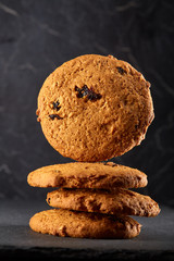 Lowkey picture of stack of chocolate chip cookies on dark stony background, close-up, shallow depth of field