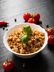 Buckwheat porridge kasha in a bowl on dark wooden background