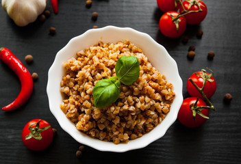 Buckwheat porridge kasha in a bowl on dark wooden background