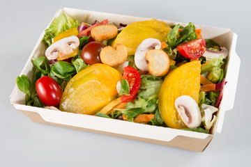 Greek salad in paper carton kraft on white background. Salad take away or food delivery