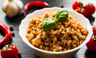 Buckwheat porridge kasha in a bowl on dark wooden background