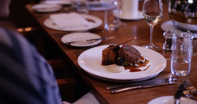 4K Waitress sets down dishes on the table in elegant gourmet restaurant