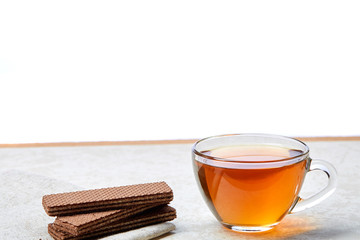 Top view close up picture of tea in transparent cup with chocolate waffles on a cotton napkin on white background