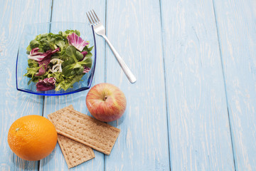 Fresh green leaves of vegetables arugula, salad, on a wooden table. Bright orange and bread