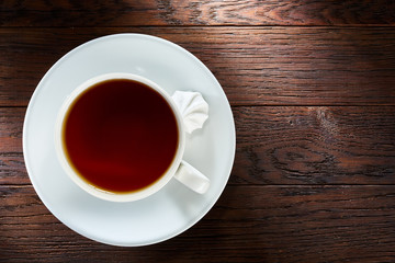 Cup of tea with meringues on a wooden background, top view