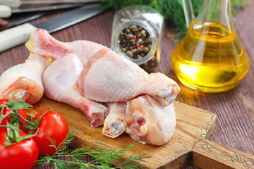 Raw chicken legs with spices and vegetables on a cutting board