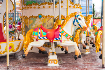 Fototapeta na wymiar Old French carousel in a holiday park. Three horses and airplane on a traditional fairground vintage carousel. Merry-go-round with horses.