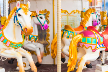 Old French carousel in a holiday park. Three horses and airplane on a traditional fairground vintage carousel. Merry-go-round with horses.