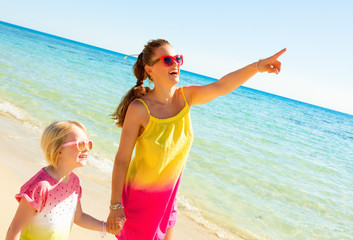 mother and child on seashore pointing at something and walking