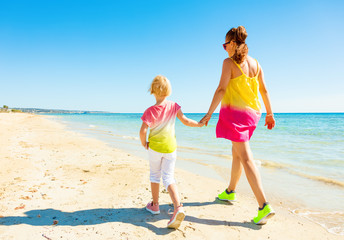 Naklejka premium modern mother and daughter on seacoast walking