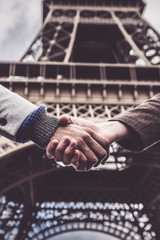 Two Men Shaking Hands By The Eiffel Tower