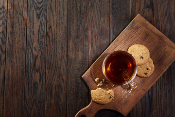 Fototapeta na wymiar Cup of tea with cookies on a cutting board on a wooden background, top view