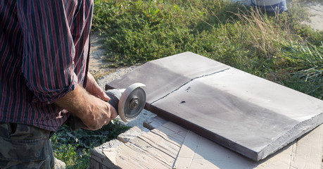 Construction worker cutting concrete plate for fence fundation using a cut-off saw.