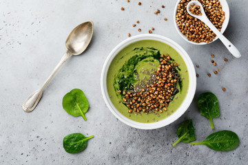 Useful smoothies from spinach with buckwheat flakes in ceramic bowls on gray concrete table background. Selective focus. Top view. Copy space.