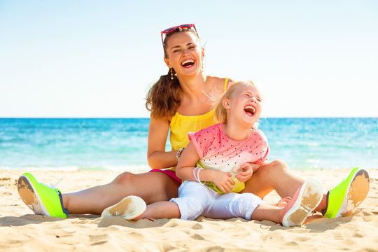 smiling trendy mother and daughter on seashore having fun time