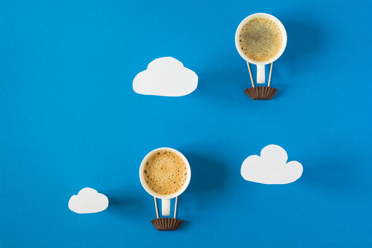 Air balloon from cups of espresso with paper clouds. Paper art style or craft.