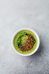 Useful smoothies from spinach with buckwheat flakes in ceramic bowls on gray concrete table background. Selective focus. Top view. Copy space.
