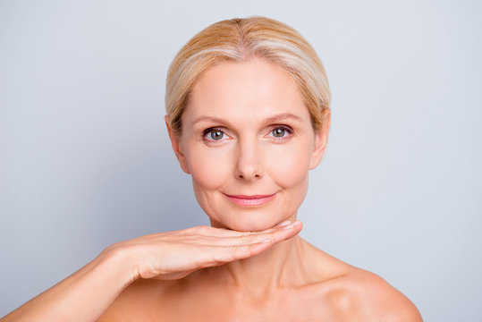 Pretty, attractive, charming,  woman demonstrate, show, present her perfect skin after peeling, lotion, mask, isolated on grey background, holding hand under chin, treatment, therapy concept