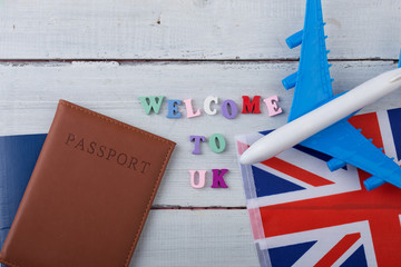 Travel time - colorful wooden letters with text "Welcome to UK" , flag of the United Kingdom, airplane model, passport