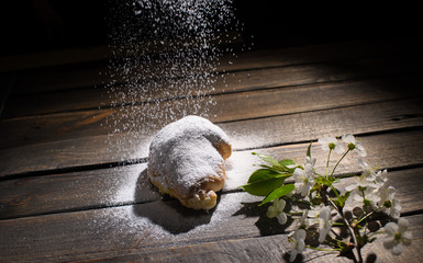 croissant on wooden desk with falling powdered sugar